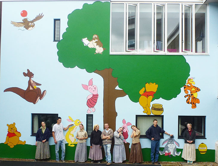 Darvell Bruderhof members with the painted mural in the courtyard of the Kipling Children's Ward, Conquest Hospital