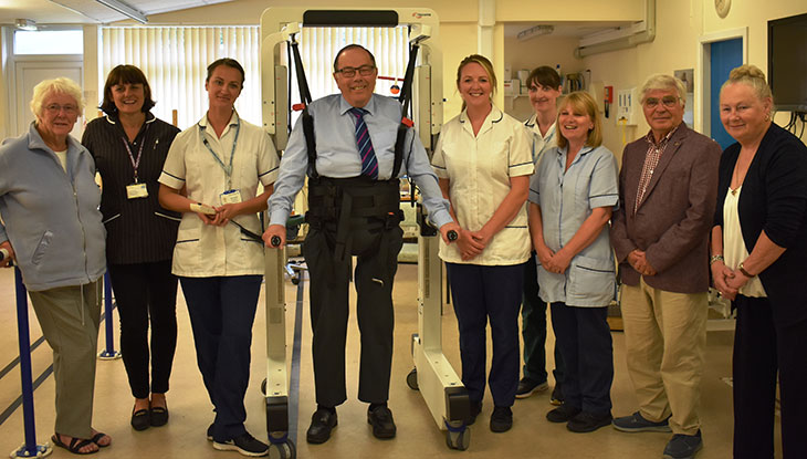 Bexhill Hospital League of Friends Chairman, Stuart Earl in the robotic hoist, Emma Quigley Team Lead Physiotherapist to right of hoist, along with Irvine unit staff and representatives of Bexhill Hospital League of Friends