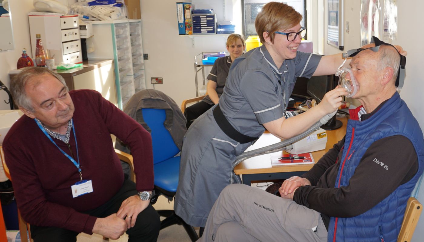 Georgie Luxford, Senior Specialist Respiratory Practitioner, demonstrating a ventilator on Richard Wray with Bill Hamilton from Friends of Conquest Hospital