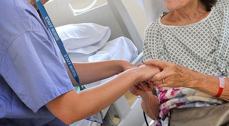 Staff nurse holding the hands of a patient