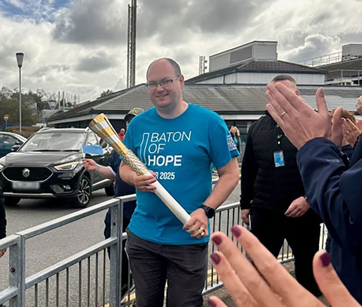 Baton bearer Mark Fincher carries the baton through Conquest Hospital