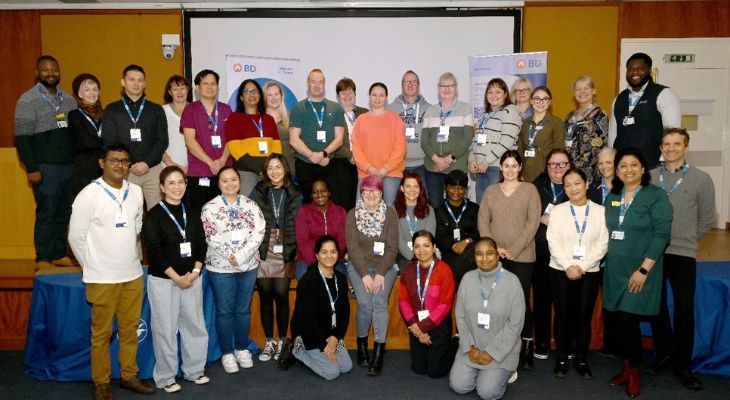 A large group of people stand smiling.
